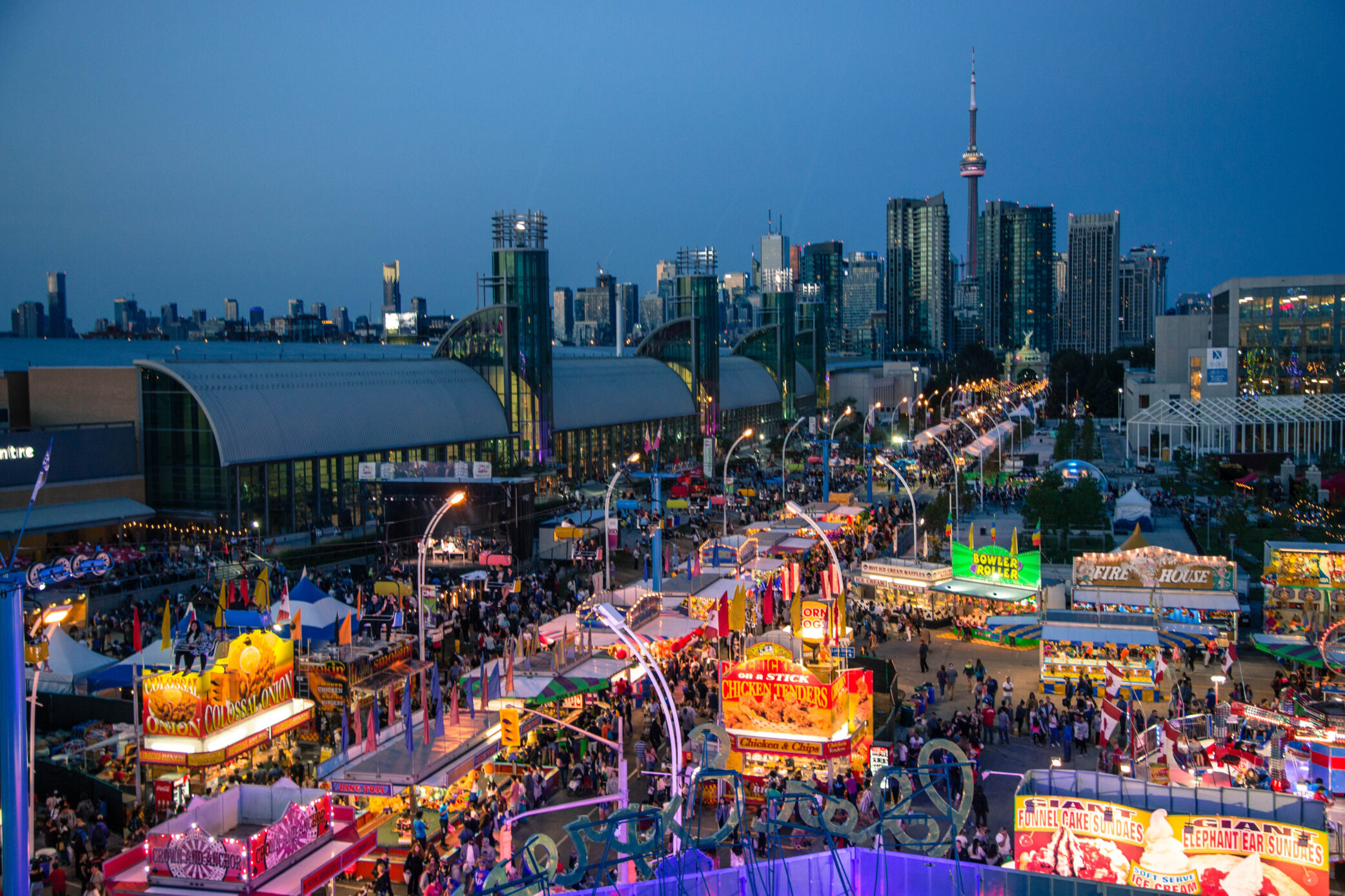 Aerial view of the CNE Midway at dusk. Image includes the Enercare Centre, the CN Tower and part of Hotel X.