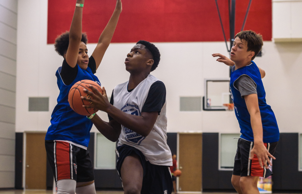 Three young athletes playing a game of basketball.