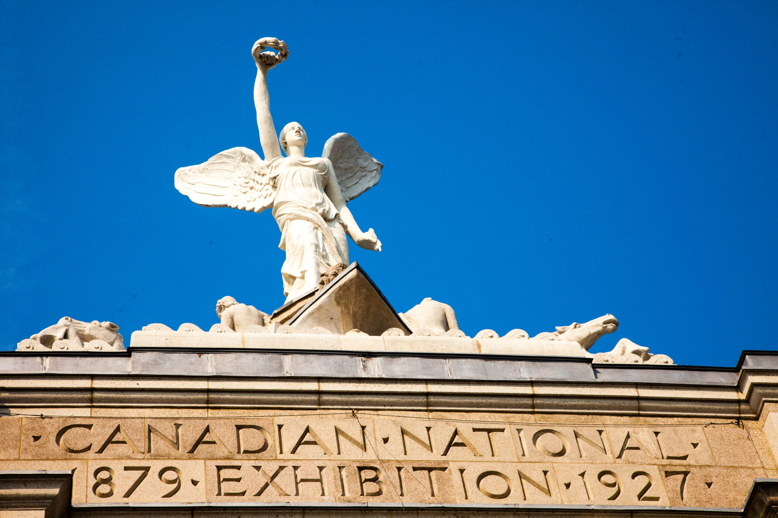 View from below of the angel on top of the Princes' Gates during the day.