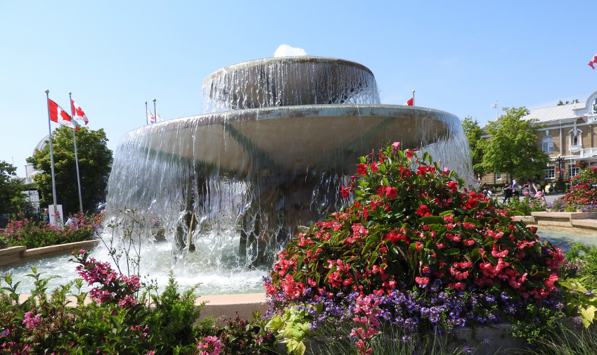 Princess Margaret fountain in the daytime. With Canadian flags in the background and a portion of the Administration building showing.