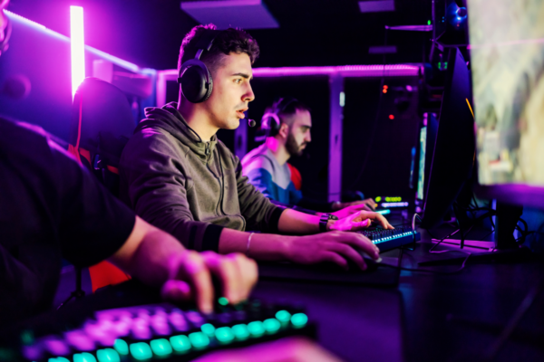 Gaming Garage. Image of three people playing computer games on a desktop computer.