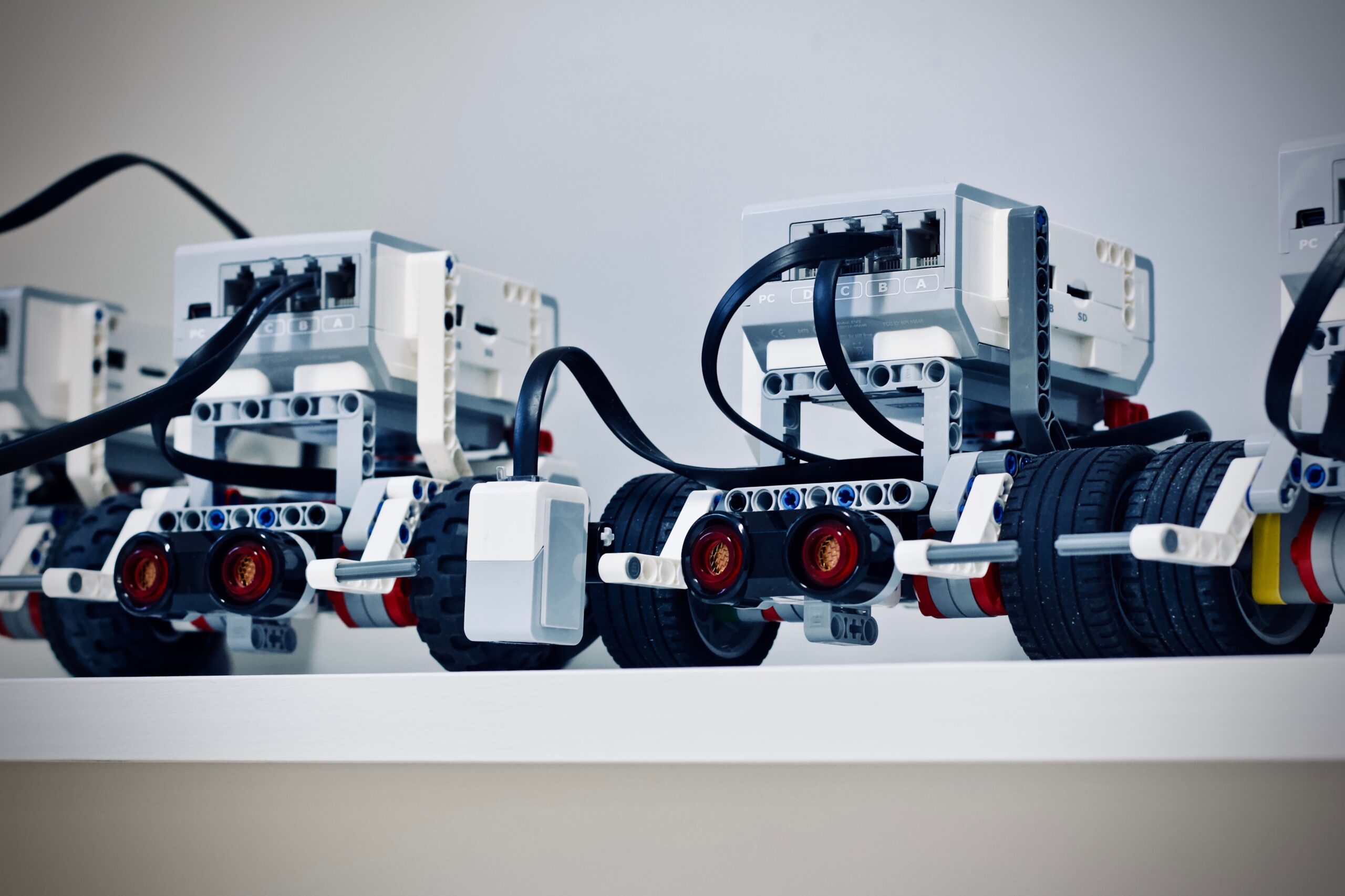 A row of four robots where only two of them are clearly visible. Robots are displayed on a shelf which is in front of a white background.