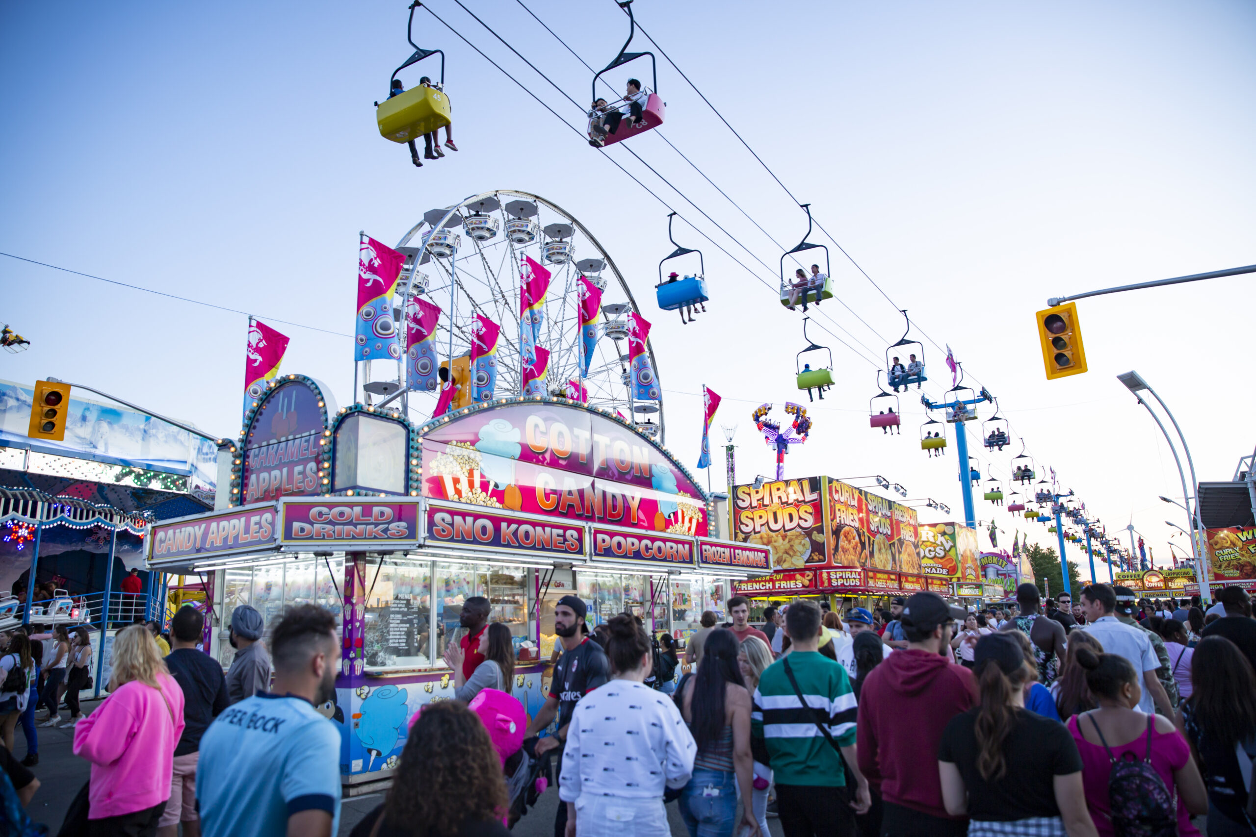 Image taken from below the sky lift and of crowds enjoying the midway at dusk.