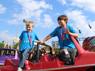 Image of two young children climbing out of a midway ride.