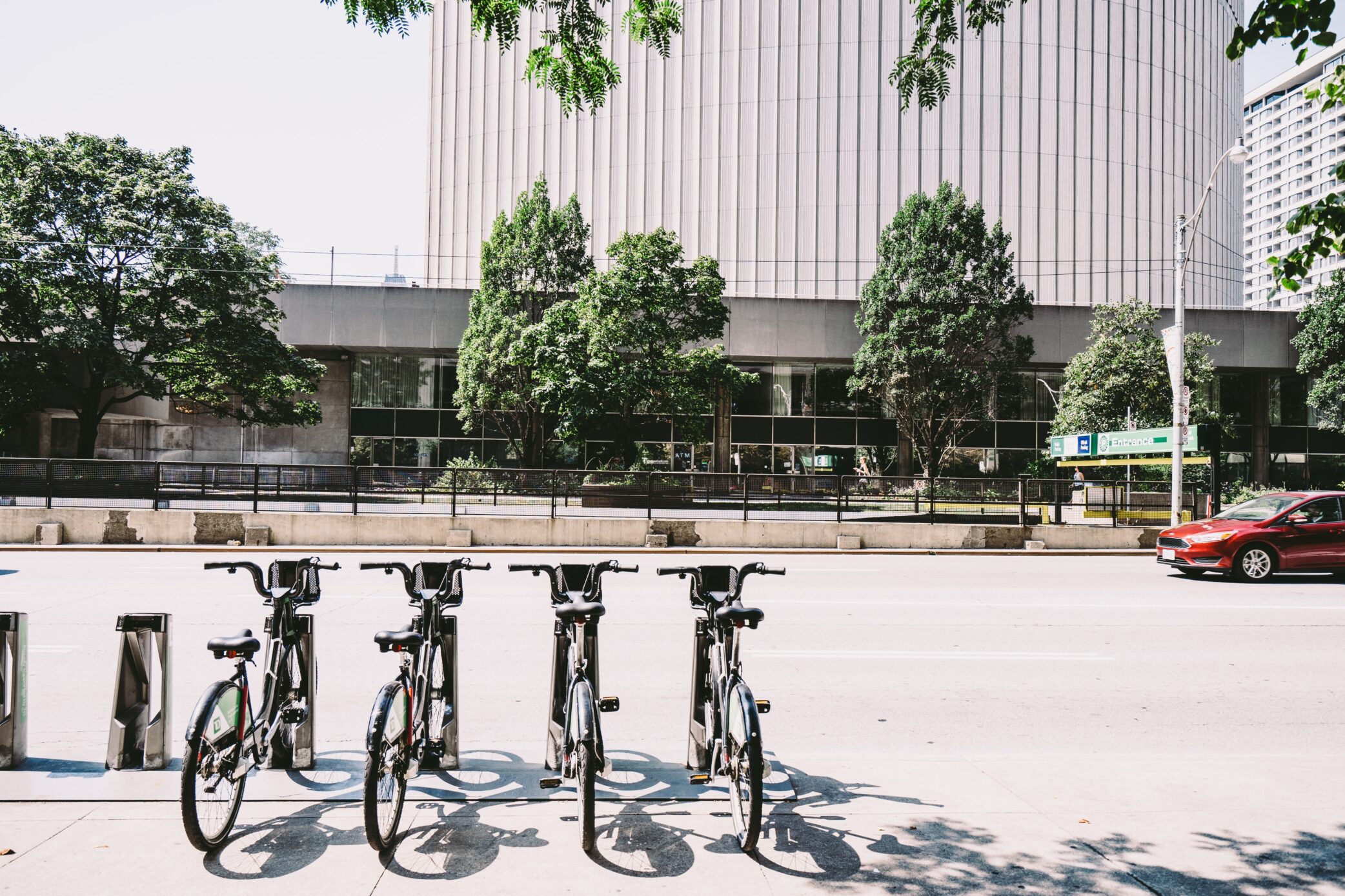 Image of bicycles parked on the side of the street in front of a building.