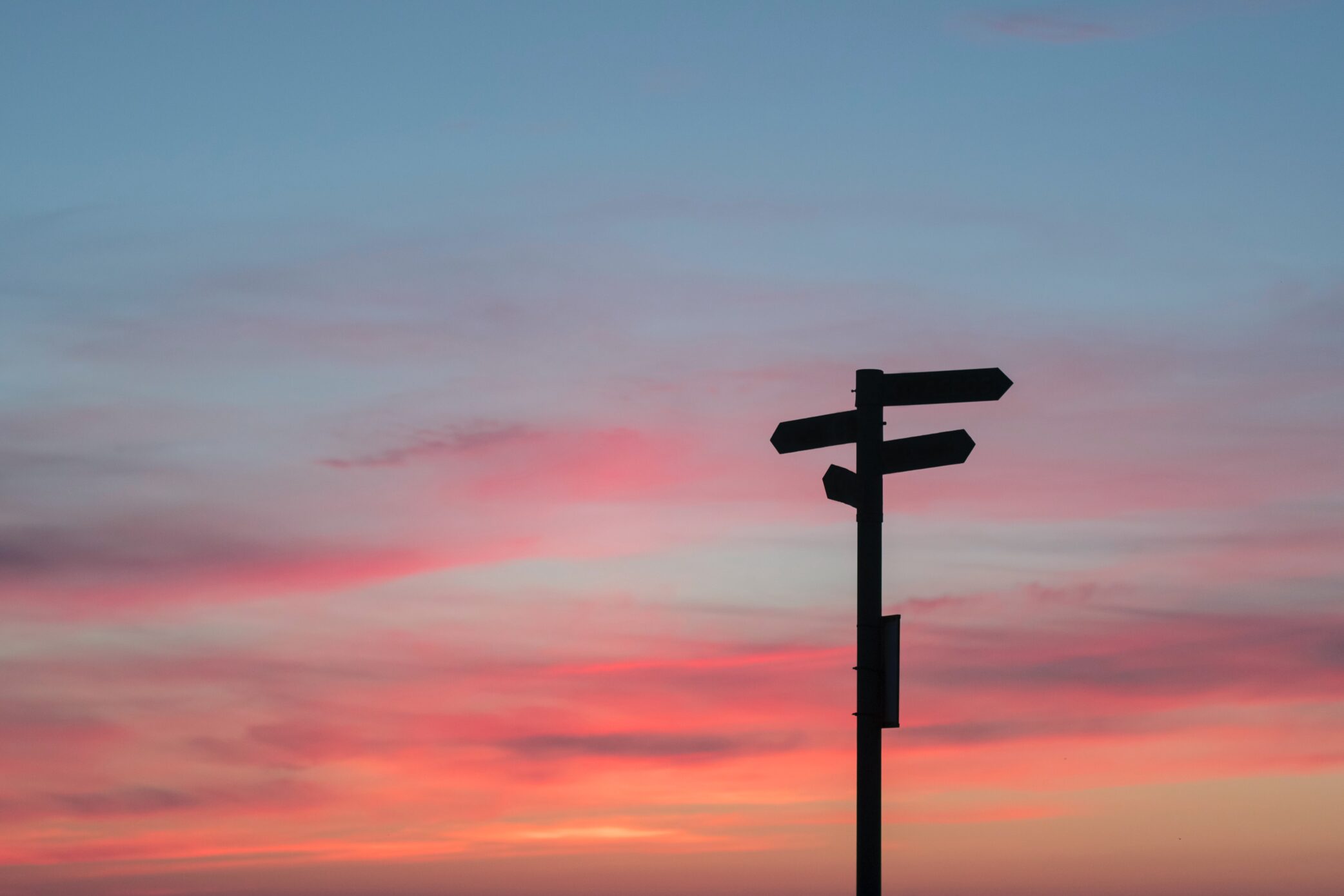A sign post with a blue and pink sky.