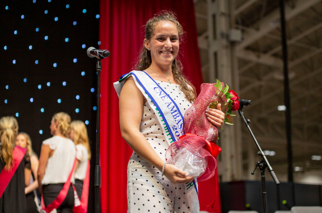 Image of the Ambassador of the Fairs Competition Winner holding flowers on stage.