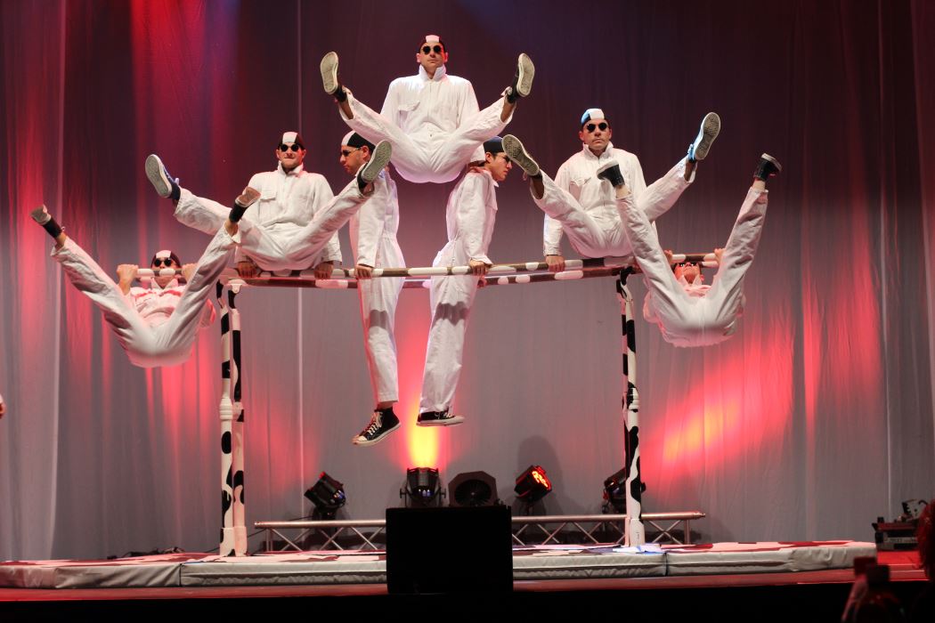7 performers in white jumpers performing acrobatics