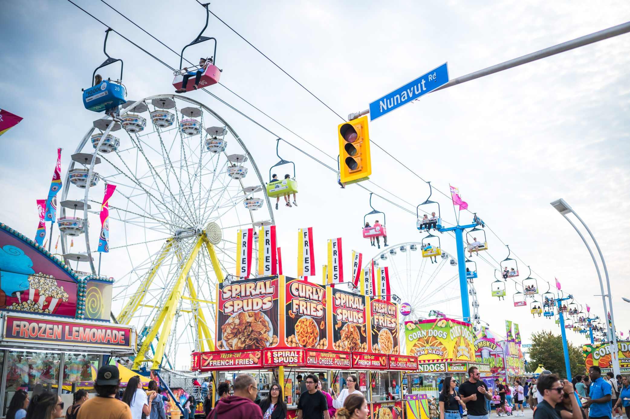 CNE midway during the day with Ferris Wheel in the background.